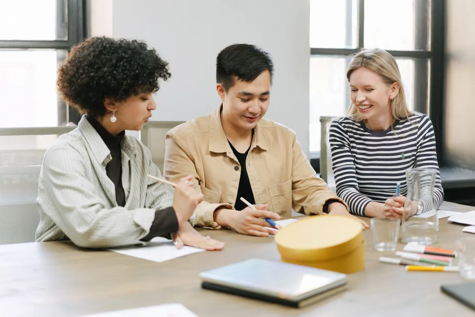 Three colleagues collaborating around a table in a bright office